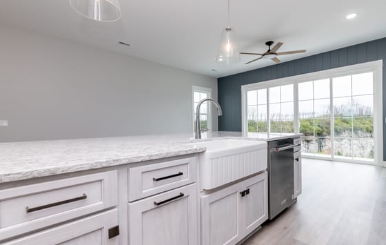Kitchen island with a fluted farmhouse sink and quartz top, looking through to the sliding doors and treeline
