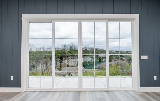 Four-panel sliding glass doors centred on a navy shiplap wall, looking out over a flooded limestone quarry
